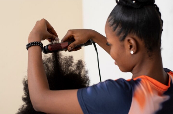 Using a flat iron to straighten natural 4C hair—highlighting the need for heat protection and moderation