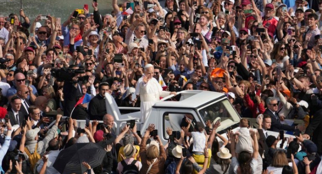 Pope Leo XIV greets the faithful from the Popemobile as crowds cheer and take photos during his inauguration at St. Peter’s Square.