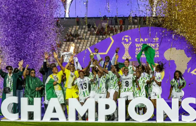 Super Falcons players lift the WAFCON trophy in celebration